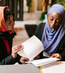 A pair of students viewing papers on a desk.