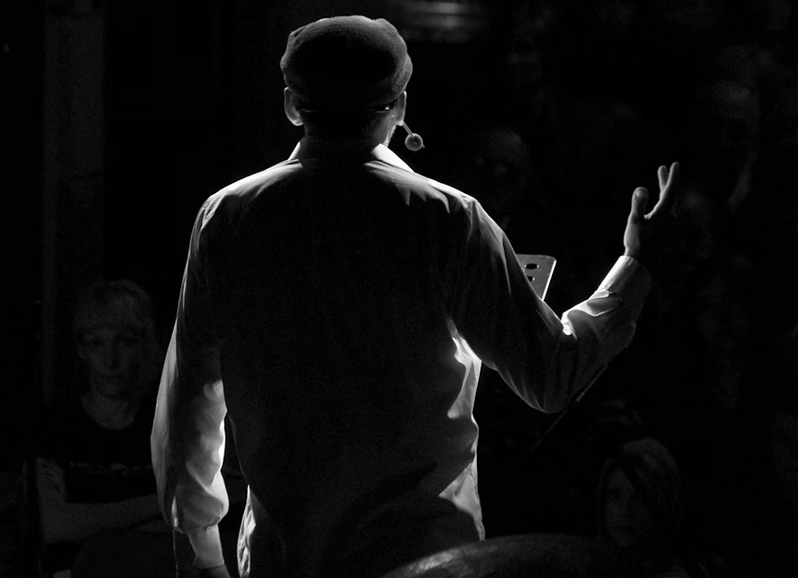 Silhouette of a man making a speech on a stage.