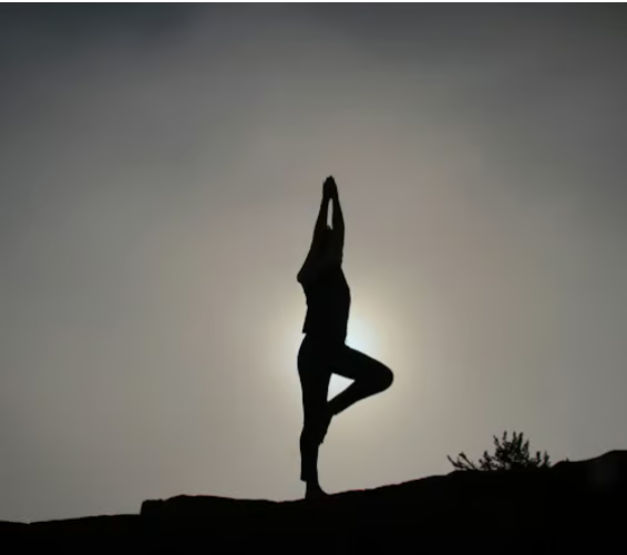 survivor health and healing Silhouette of a woman doing yoga on a mountain in the sunset.